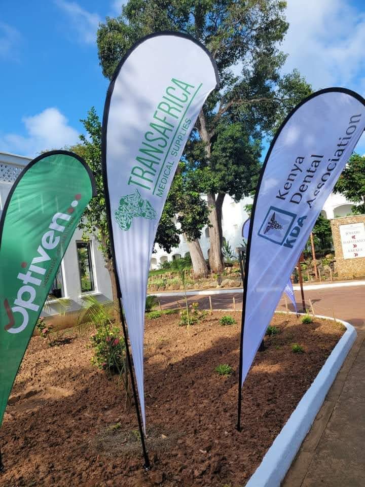 Optiven, TransAfrica and Kenya Dental Association branded feather flags in a garden setting